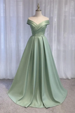 Green evening gown on a mannequin against a white curtain background