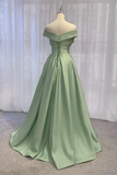 Green evening gown on a mannequin against a white curtain background