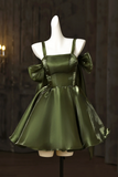 Green satin dress with bow details on a mannequin against a dark background