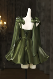Green satin dress with cape on a mannequin against a dark background