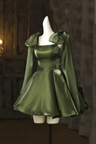 Green satin dress with matching cape on a mannequin against a dark background
