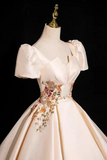 Elegant white gown with floral embroidery on a mannequin against a black background