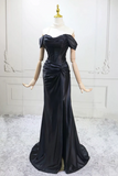 Black evening gown on a mannequin against a white wall.