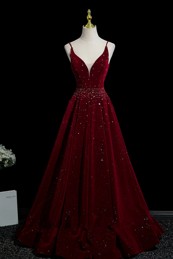 Burgundy evening gown with beading on a mannequin against a black background