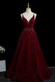 Burgundy evening gown with beading on a mannequin against a black background