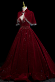 Red evening gown with a cape on a mannequin against a black background