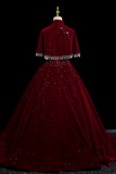 Burgundy evening gown with sequin details on a black background
