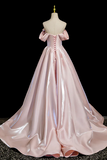 Pink satin gown on a mannequin against a black background