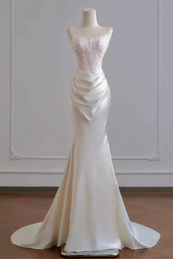 White evening gown on a mannequin against a plain background
