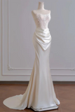 White evening gown on a mannequin against a plain wall.