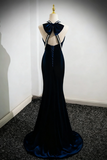 Black evening gown with bow details on a mannequin against a white wall.