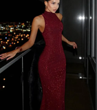 Woman in a red dress standing on a balcony with city lights in the background