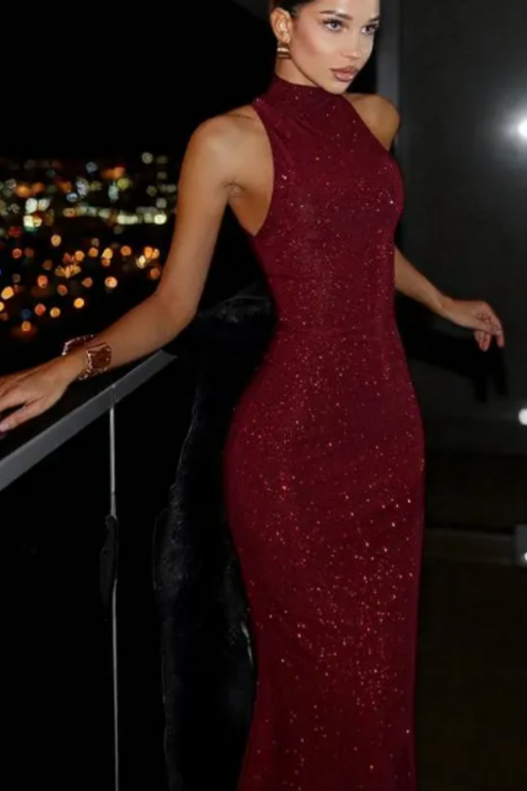 Woman in a burgundy sequin dress standing on a balcony with city lights in the background