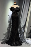 Black evening gown with sheer overlay on a mannequin against a neutral background