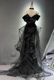 Black evening gown on a mannequin against a gray wall.