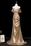 Gold evening gown on a mannequin against a black background