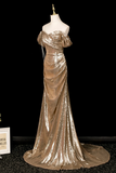 Gold evening gown on a mannequin against a black background