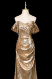 Gold evening gown on a mannequin against a black background