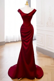 Red evening gown on a mannequin against a white wall.