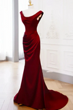 Red evening gown on a mannequin against a white wall.