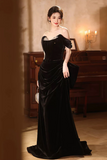 Woman in a black evening gown standing in a room with a piano.