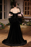 Woman wearing a black evening gown with a large bow at the back in an indoor setting.