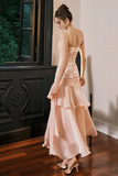 Woman in a peach evening gown standing in a room with wooden flooring and a decorative wall.