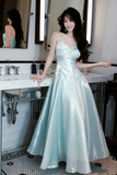 Woman in a light blue evening gown standing in a bathroom.