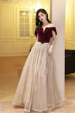 Woman in a burgundy top and beige skirt standing in an elegant interior setting.