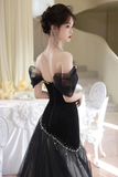 Woman in a black evening gown with sheer sleeves in an elegant indoor setting