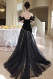 Woman in a black evening gown with sheer overlay in an elegant room.