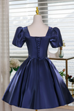 Navy blue satin dress on a mannequin with a blurred indoor background