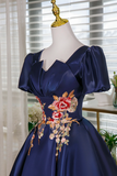 Navy blue dress with floral embroidery on a mannequin against a blurred indoor background