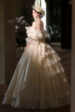 Woman in a white lace wedding dress standing indoors with soft lighting.