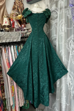 Green lace dress on a mannequin against a patterned curtain and fabric background