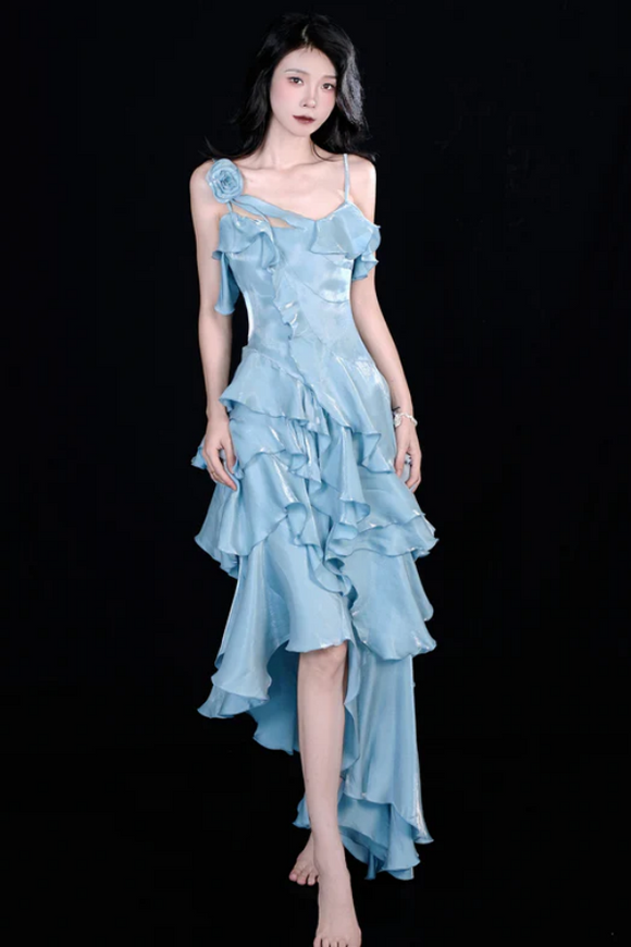 Woman wearing a light blue ruffled dress against a black background