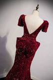 Red sequin evening gown on a mannequin against a gray background