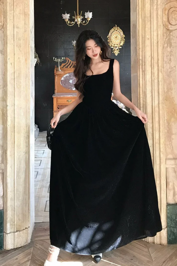 Woman in a black dress standing in an elegant interior setting.