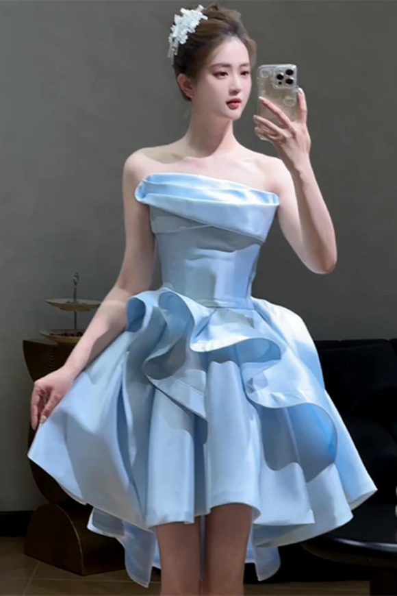 Woman in a light blue strapless dress with large floral accents taking a selfie.