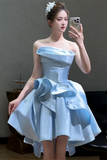 Woman in a light blue strapless dress with large floral accents taking a selfie.