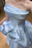 Light blue off-shoulder dress with ruffled layers on a wooden floor.