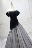Black and gray evening gown with sequin embellishments on a mannequin against a white wall.