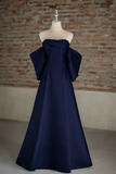 Navy blue strapless gown on a mannequin against a brick wall.