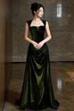 Woman wearing a green velvet gown in a dimly lit room.