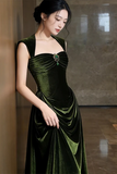 Woman wearing a green velvet dress against a marble wall.