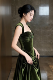 Woman wearing a green velvet dress against a stone wall.