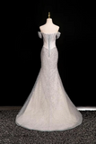 Silver off-shoulder evening gown on a mannequin against a black background