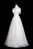 White evening gown on a mannequin against a black background