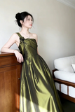 Woman in a green dress standing indoors with a neutral background
