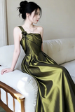 Woman in a green satin dress sitting on a white couch.